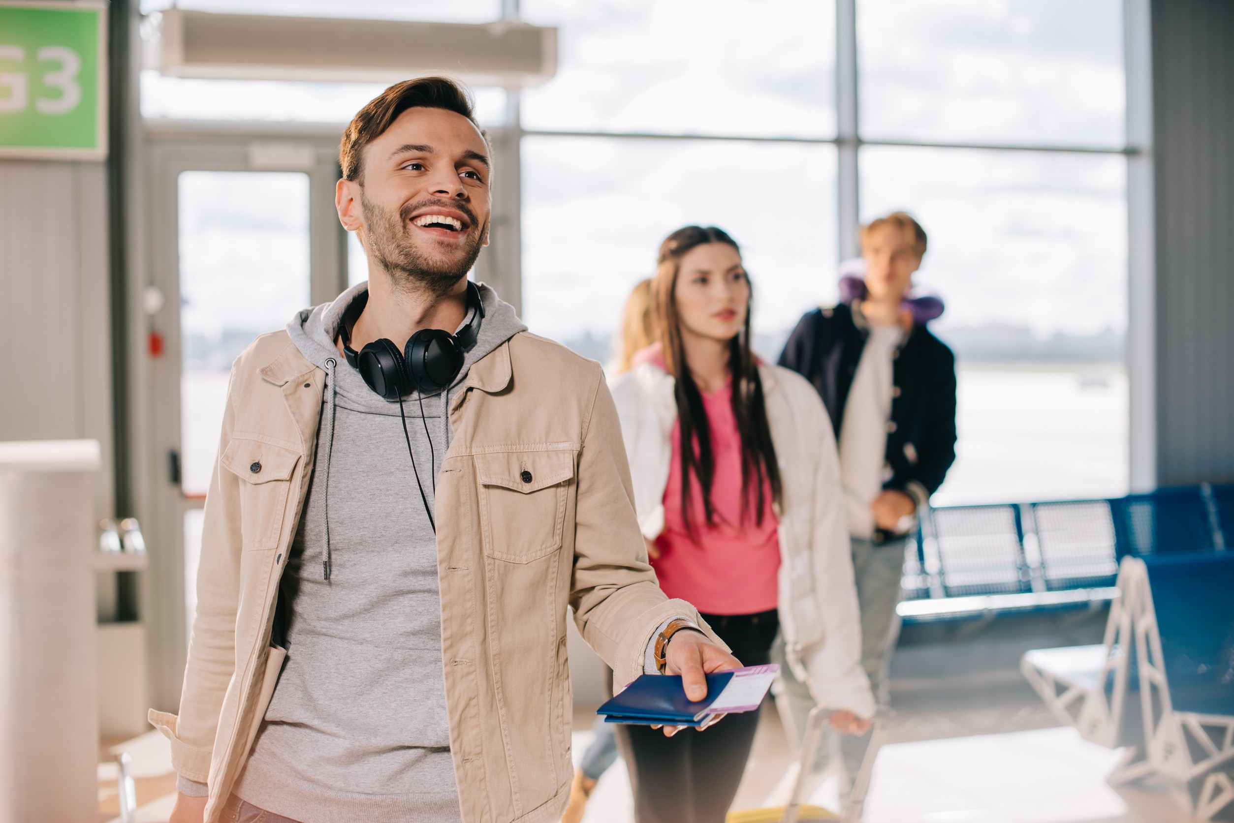 Smiling Young Man Holding Passports And Boarding Passes In Airport