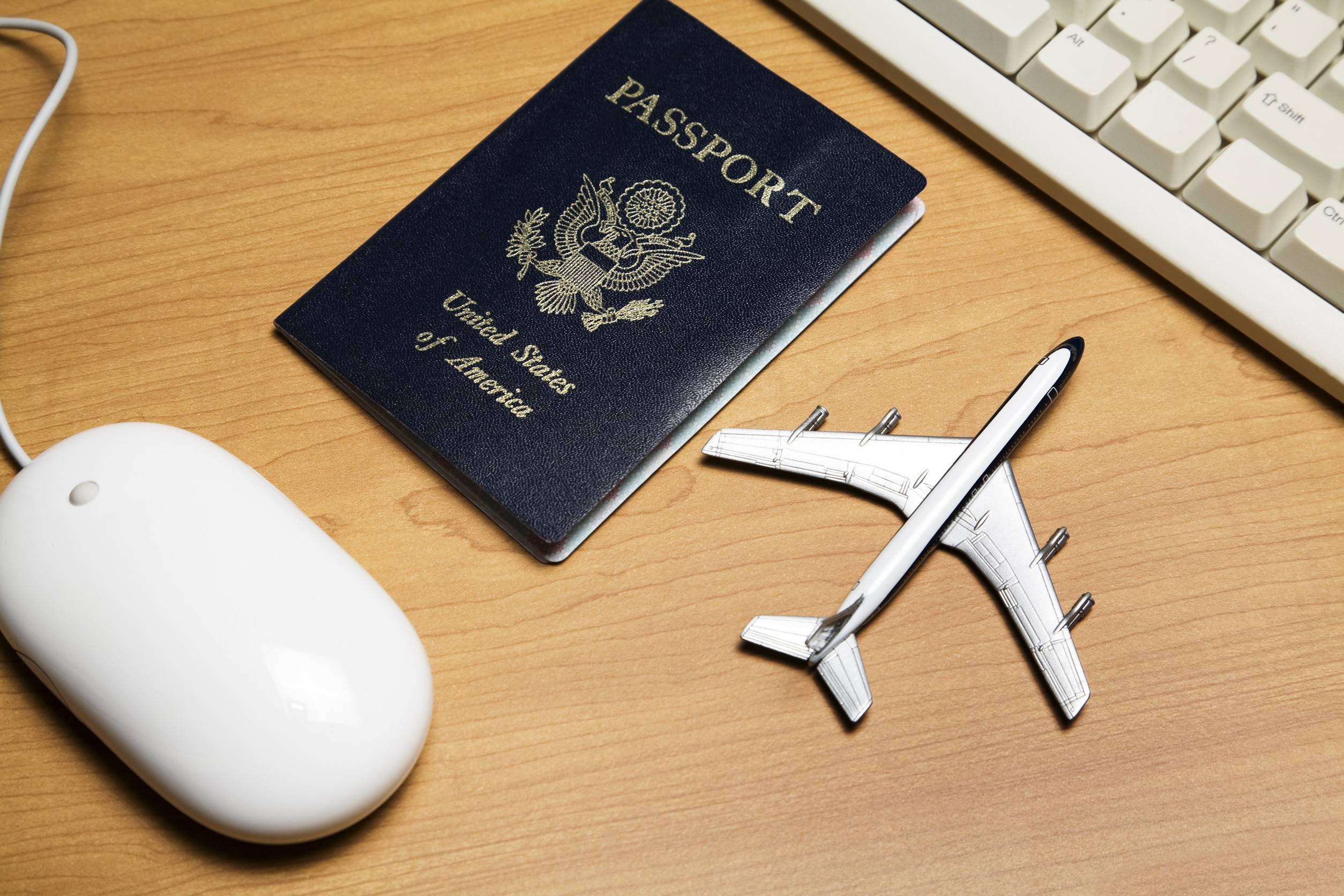 White Computer Mouse Toy Airplane And Passport On A Wood